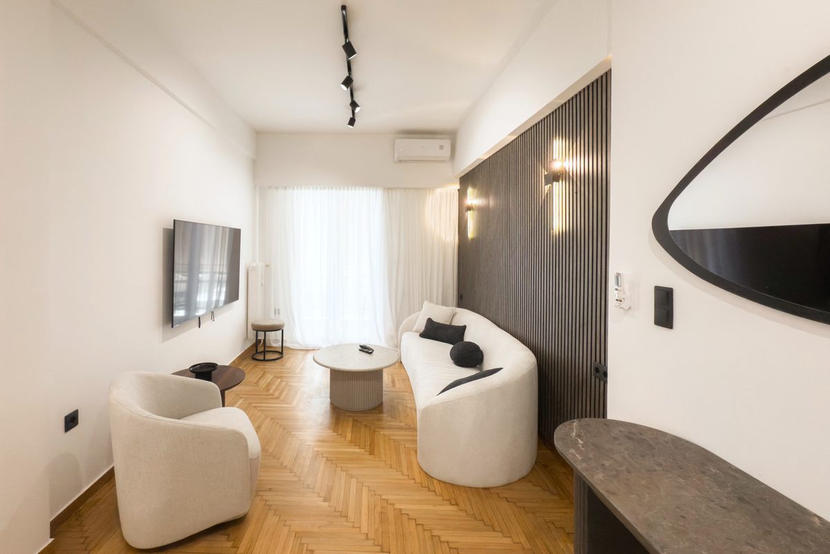 Living room with herringbone parquet, curved sofa and dark slatted wall