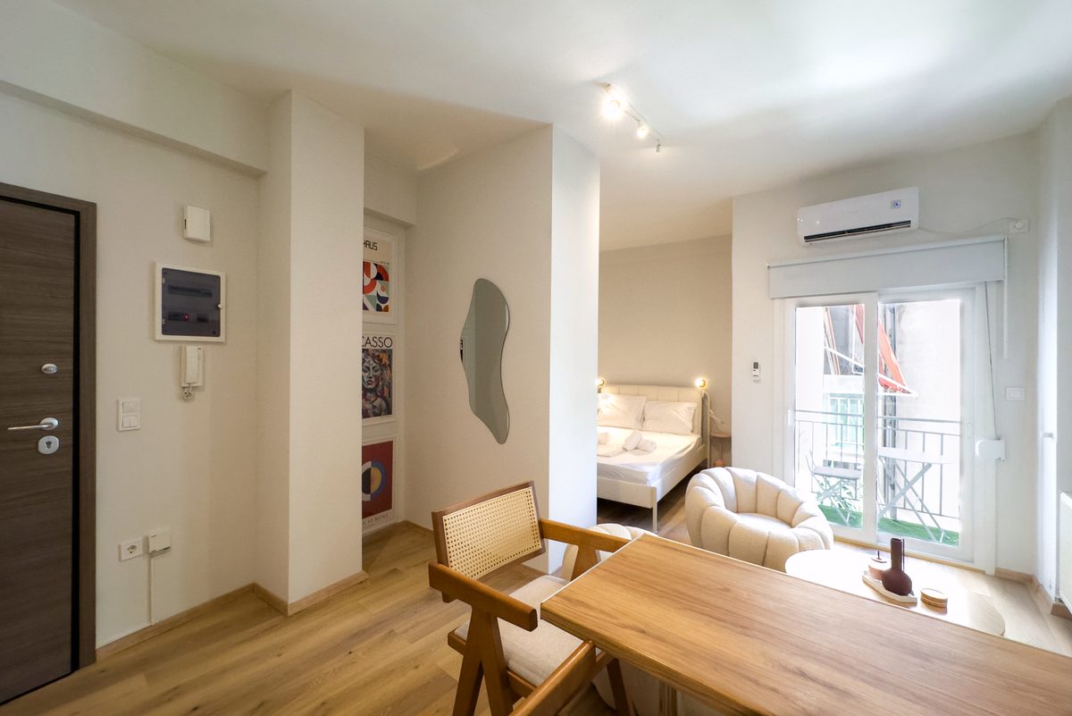 Living area with bouclé armchairs, dining table and the bed by the balcony door