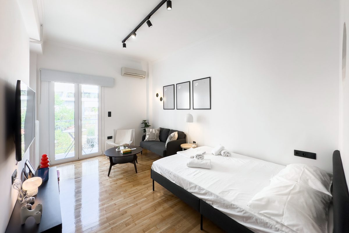 Open-plan room with bed, grey sofa and balcony door